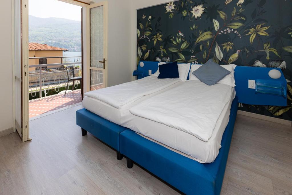 Cette chambre comprend un lit bleu et un balcon. dans l'établissement La Foresta Monteisola, à Monte Isola