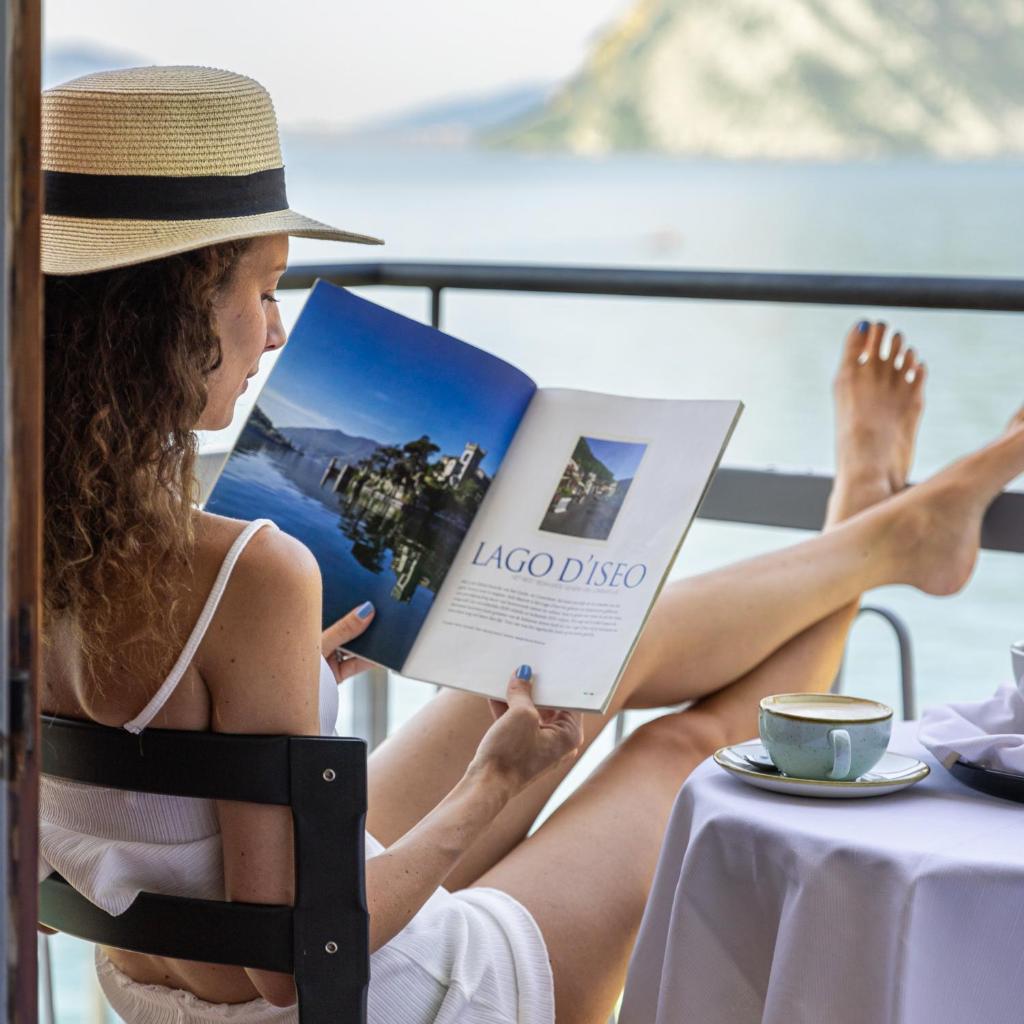 une femme assise sur une chaise en train de lire un livre dans l'établissement La Foresta Monteisola, à Monte Isola