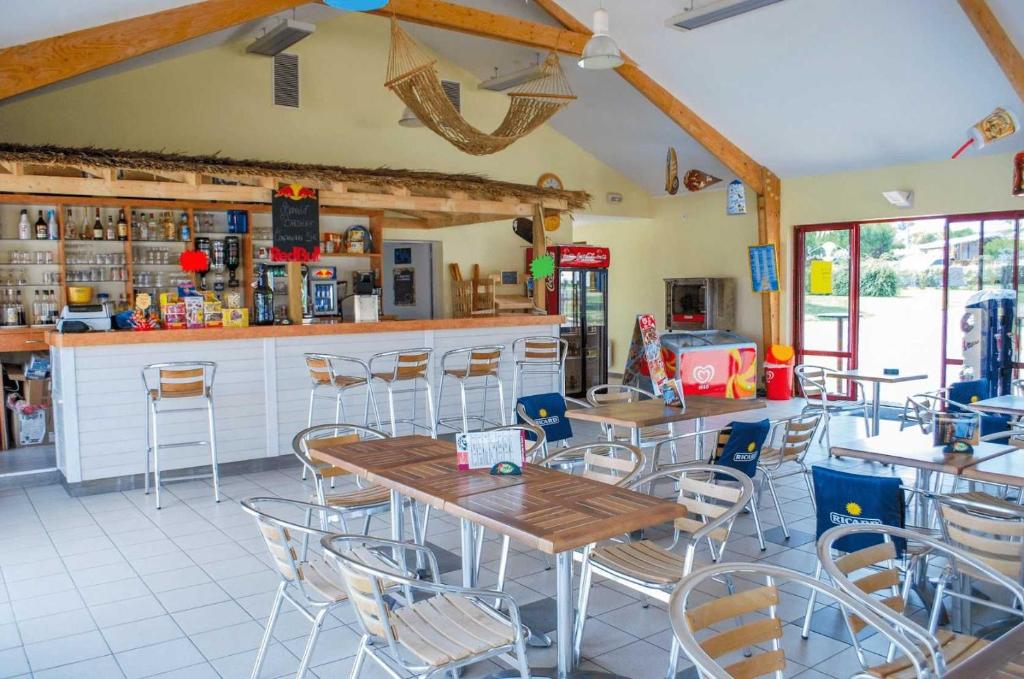 un restaurant avec des tables, des chaises et un comptoir dans l'établissement Camping - Parc aquatique - ccagehb, à Saint-Michel-Chef-Chef