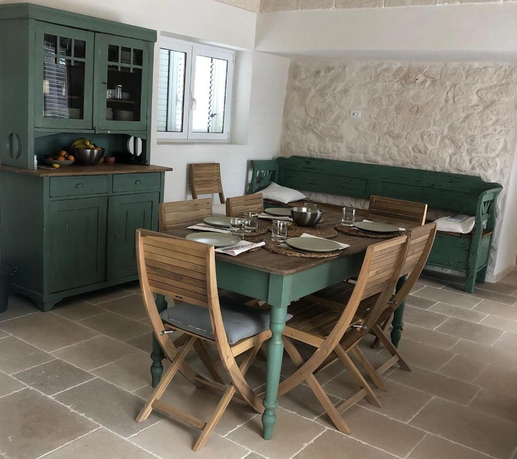 une salle à manger avec une table et des chaises vertes dans l'établissement Trullo FICOLI, à Ostuni