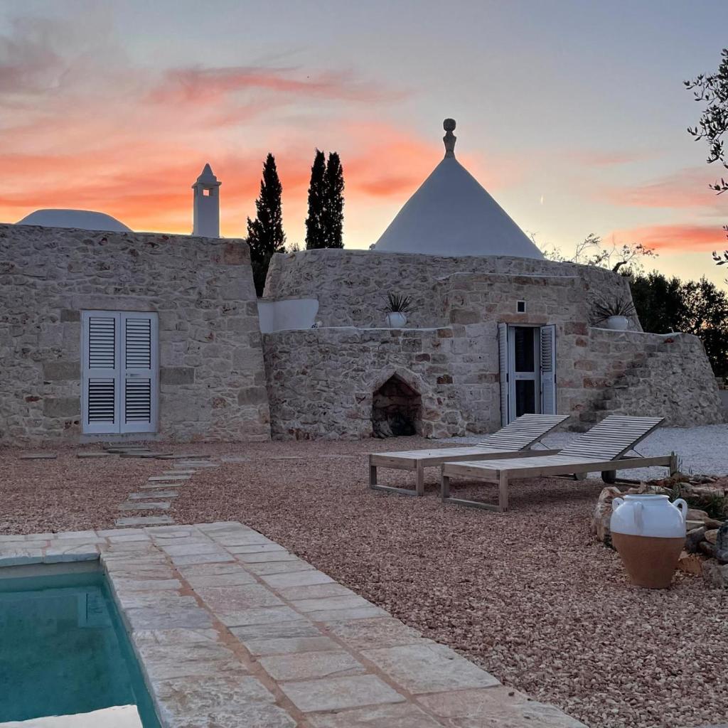 - un bâtiment en pierre avec une piscine et un coucher de soleil dans l'établissement Trullo FICOLI, à Ostuni