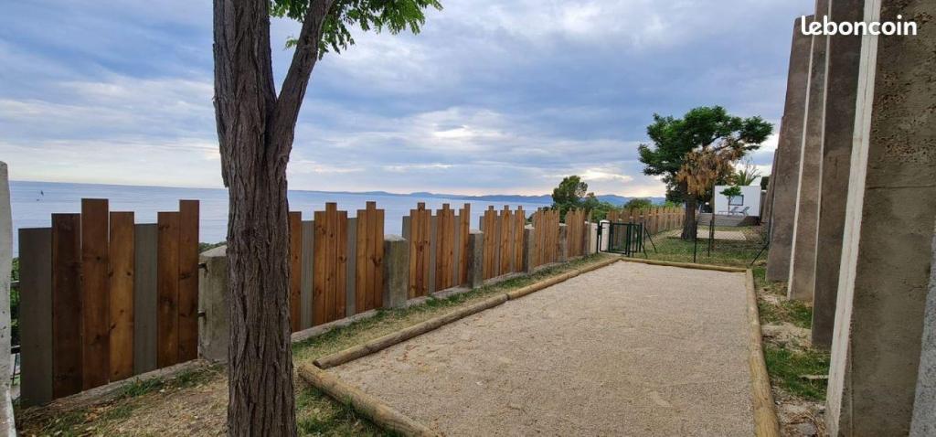 une clôture en bois avec un trottoir au bord de l'eau dans l'établissement Bungalow Mobile Home de Luxe Vue Mer Saint-Raphaël 4 personnes, à Saint-Raphaël