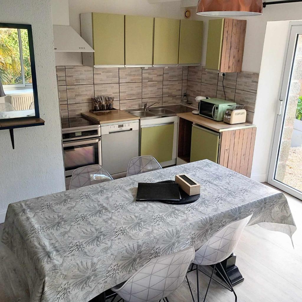 une cuisine avec une table et des chaises et une cuisine avec un comptoir dans l'établissement Gite Les Sables Blancs, à Plobannalec-Lesconil
