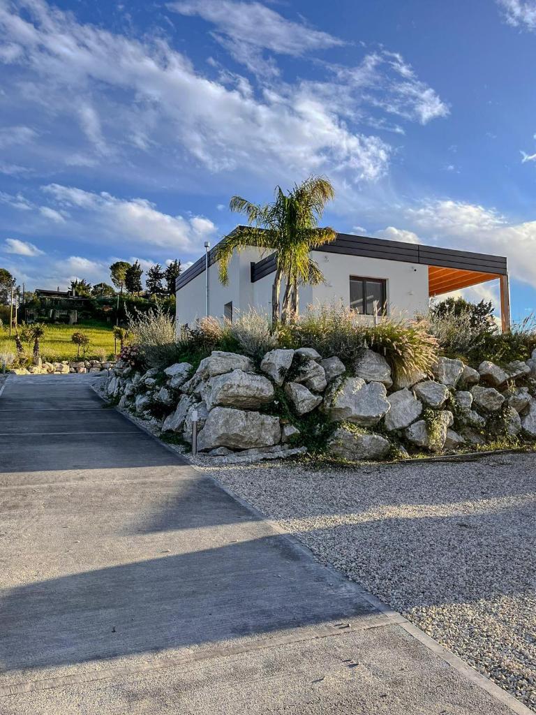 une maison avec un palmier et un mur en pierre dans l'établissement Villa Ginevra, à Santa Ninfa