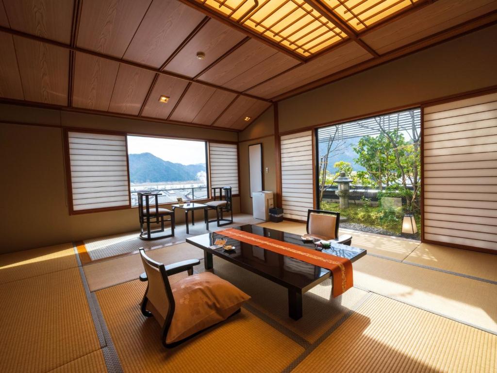 un salon avec une table, des chaises et des fenêtres dans l'établissement Kinosakinoyado Ryokufukaku, à Toyooka