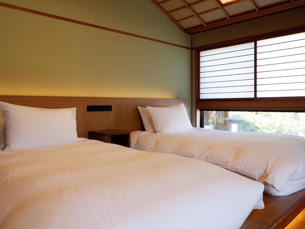 une chambre avec deux lits et une fenêtre dans l'établissement Kinosakinoyado Ryokufukaku, à Toyooka