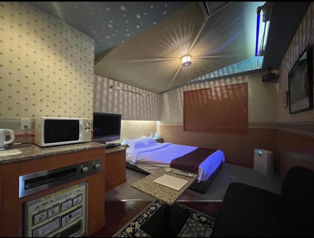 une chambre avec un lit et un bureau avec une télévision dans l'établissement ホテルビューローズマリー, à Kai