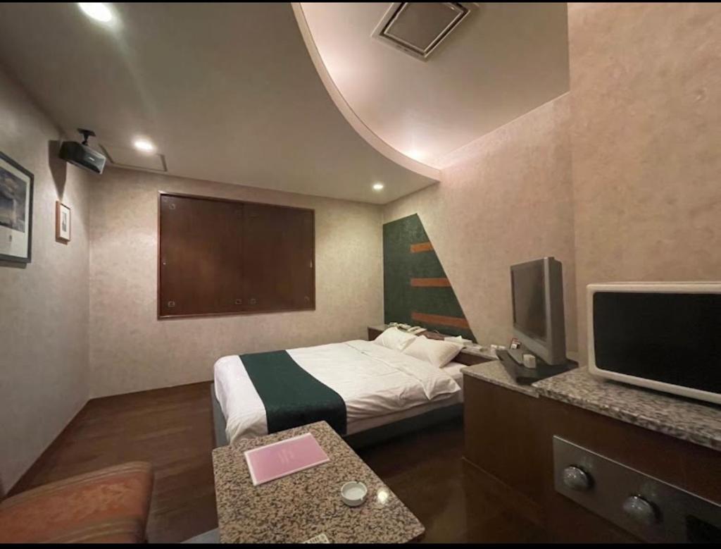 une chambre d'hôtel avec un lit et une télévision à écran plat dans l'établissement ホテルビューローズマリー, à Kai