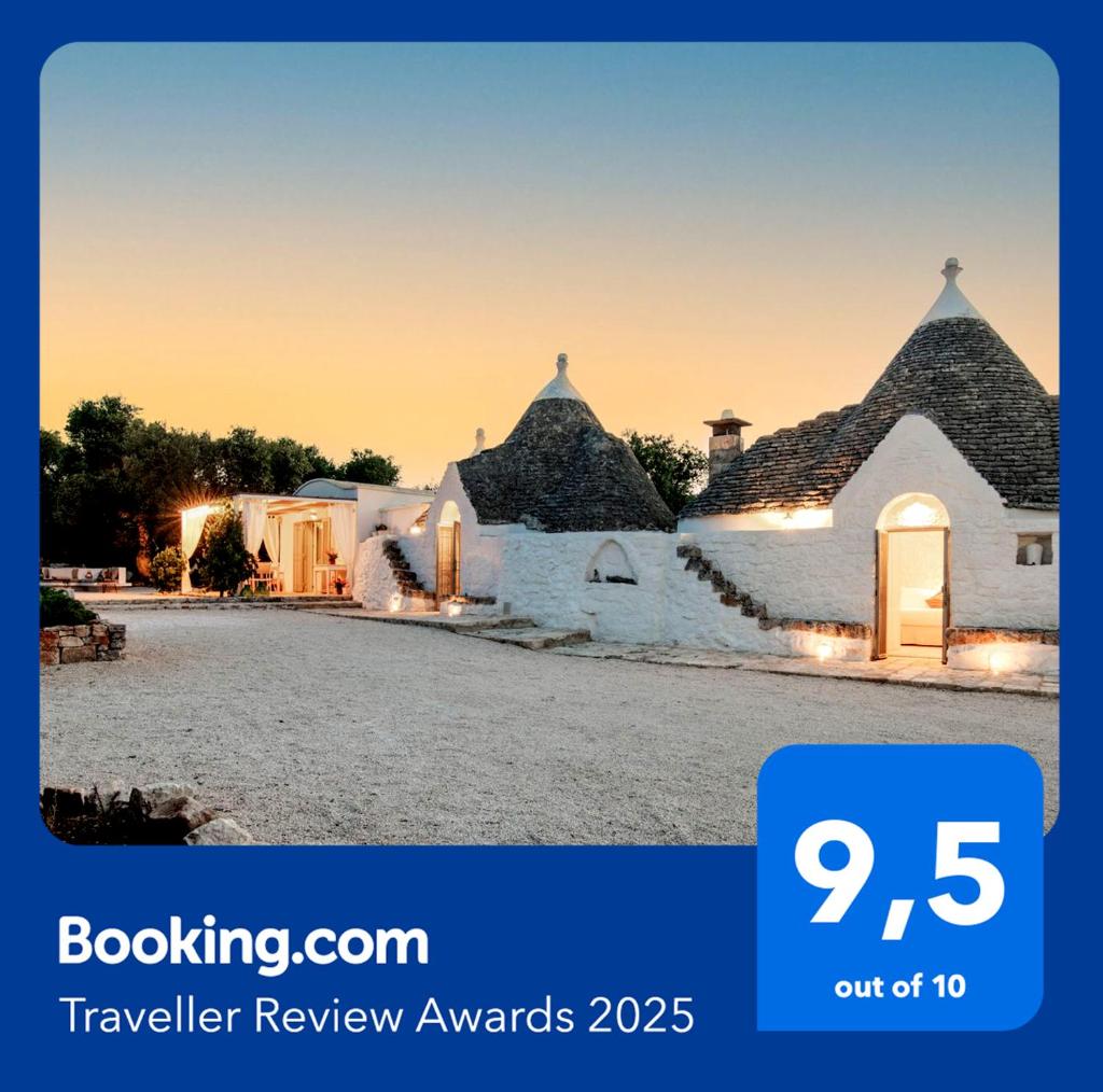 une maison blanche avec une horloge. dans l'établissement TRULLO TIPOTA with private pool, à Ceglie Messapica