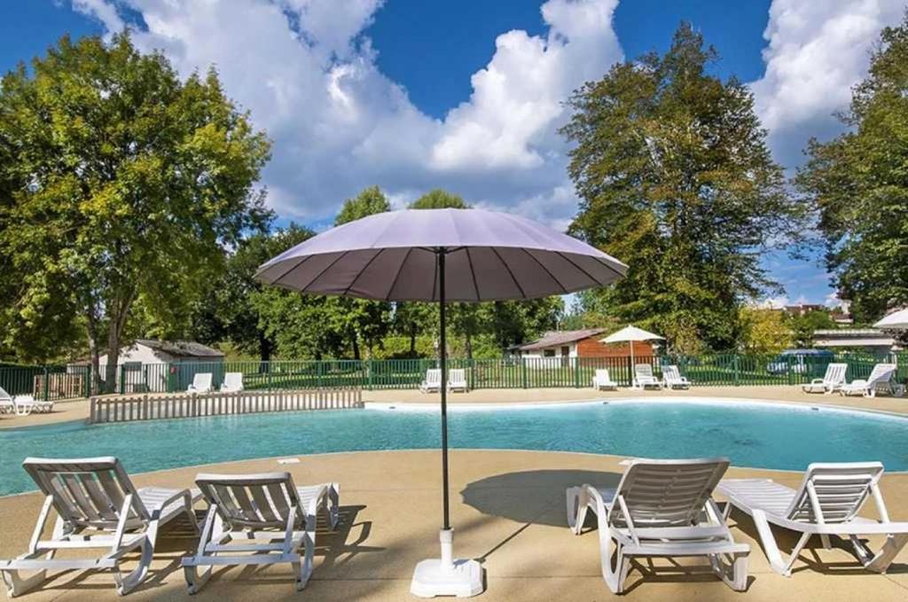 - un groupe de chaises et un parasol à côté de la piscine dans l'établissement Camping 2 étoiles - Piscine - ccab0if, à Saint-Sozy