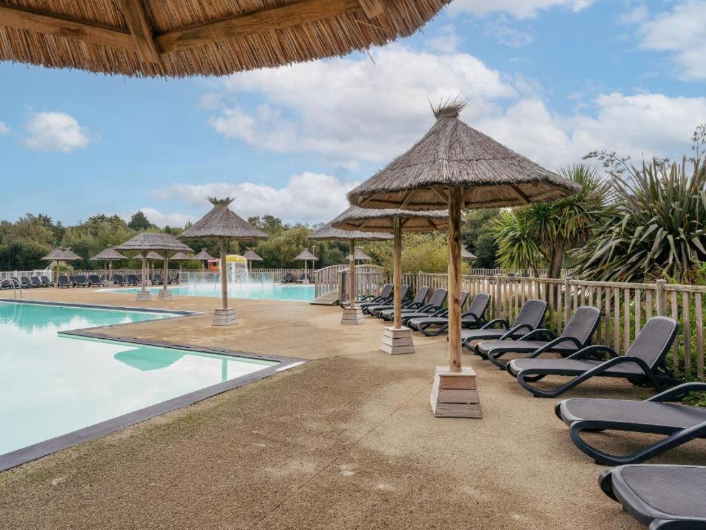 un groupe de chaises et de parasols à côté d'une piscine dans l'établissement Mobil home Bord de Mer, à Fouesnant 17 autres photos