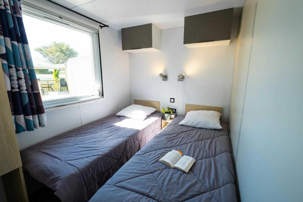 deux lits dans une petite pièce avec une fenêtre dans l'établissement Camping 4 étoiles - Parc aquatique - ef0bdc, à Martigues
