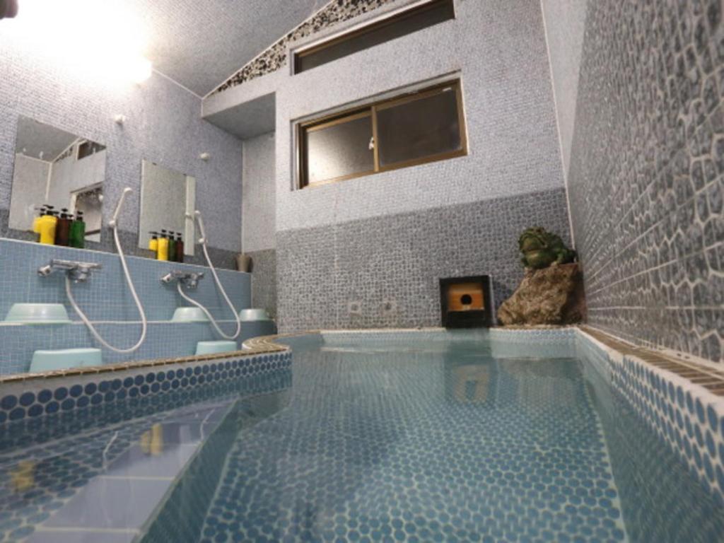 La salle de bains est pourvue d'une piscine avec douche et lavabo. dans l'établissement Hinode Ryokan, à Ise