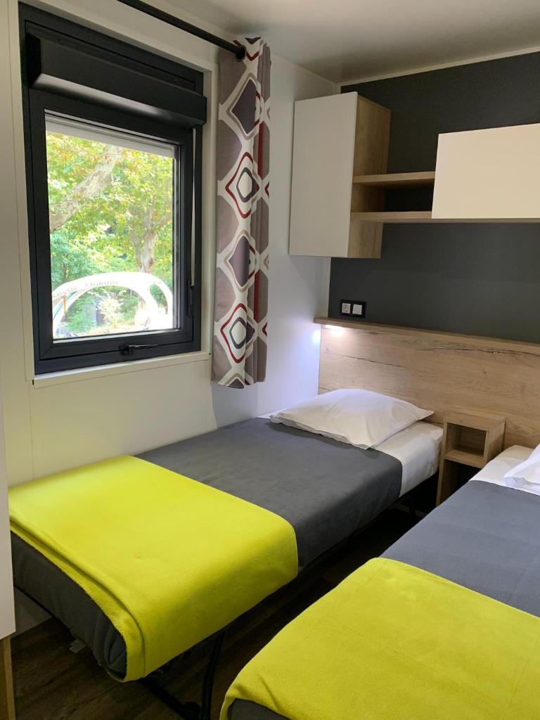 deux lits dans une chambre avec une fenêtre dans l'établissement Camping le mas des sedaries, clim, à Villefort 9 autres photos