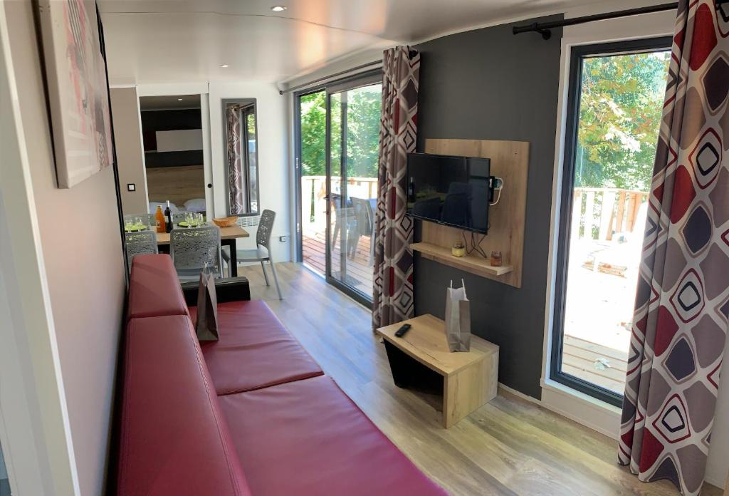 un salon avec un canapé rouge et une télévision dans l'établissement Camping le mas des sedaries, clim, à Villefort