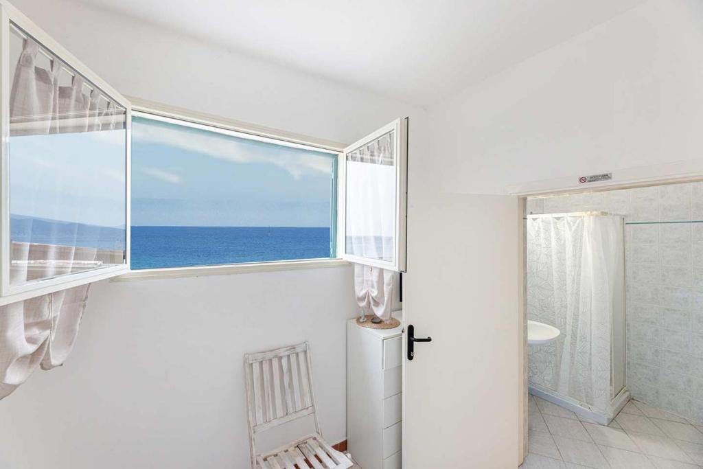 - une salle de bains blanche avec une grande fenêtre donnant sur l'océan dans l'établissement Hotel Le Ghiaie, à Portoferraio