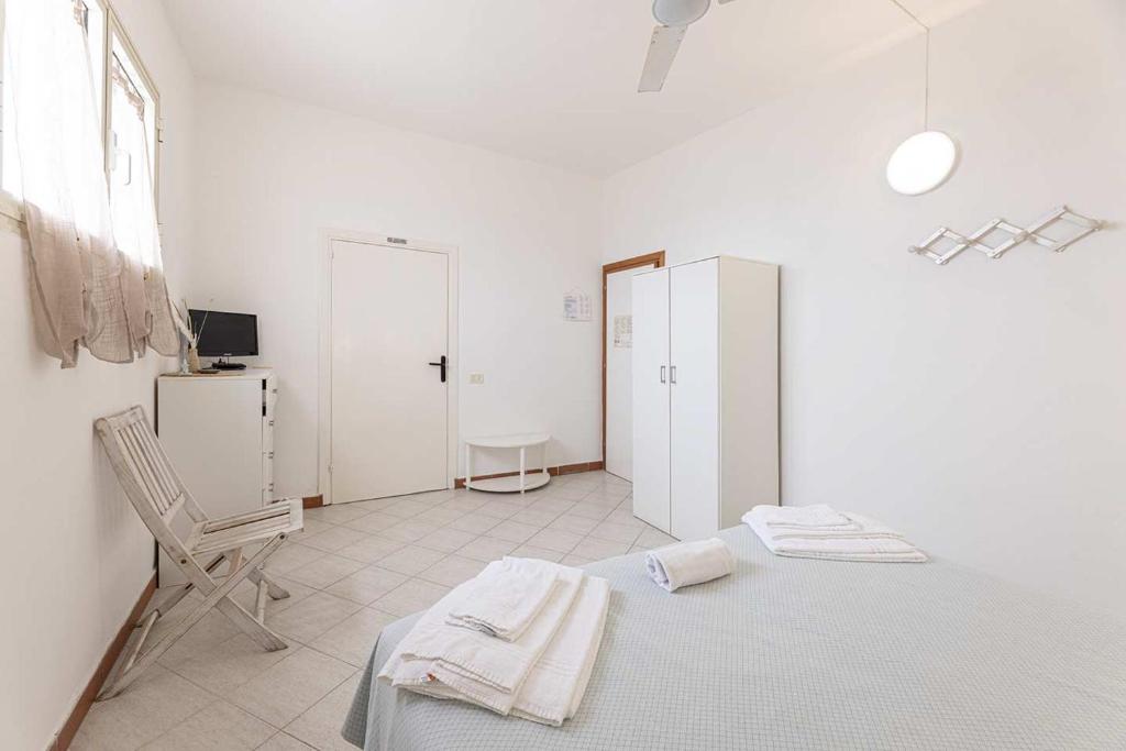 une chambre blanche avec un lit et une chaise dans l'établissement Hotel Le Ghiaie, à Portoferraio