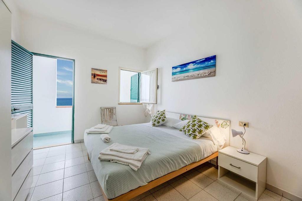 une chambre blanche avec un lit et une fenêtre dans l'établissement Hotel Le Ghiaie, à Portoferraio