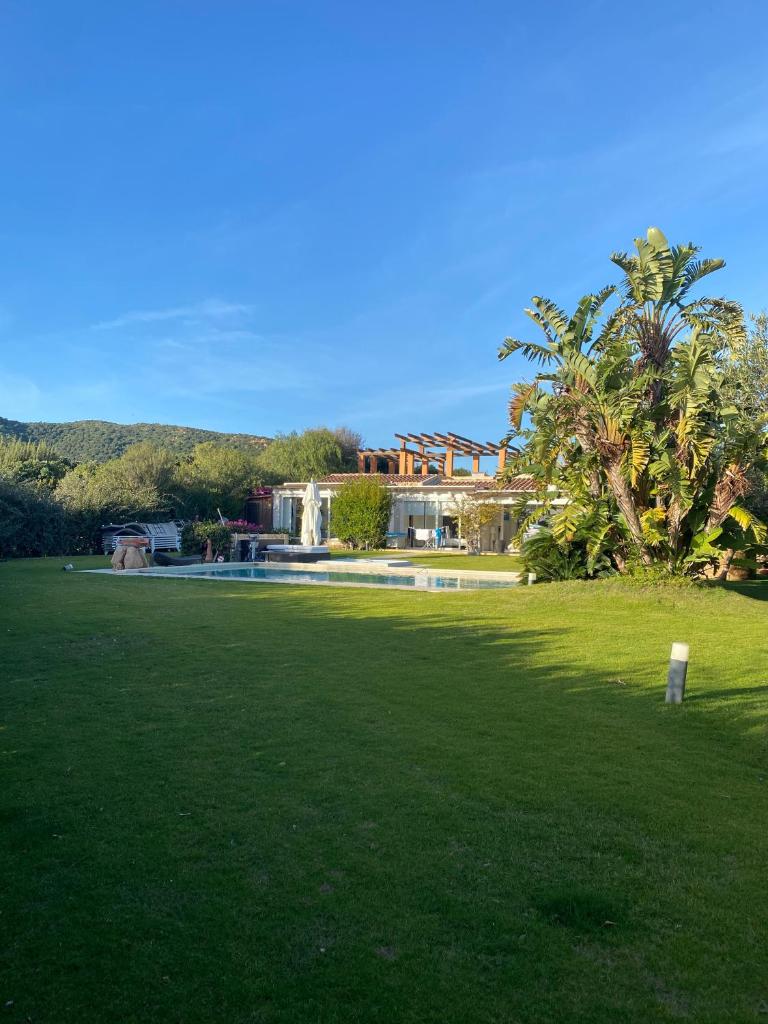 un champ vert avec une maison en arrière-plan dans l'établissement VILLA BAIRES - CHIA, à Domus de Maria