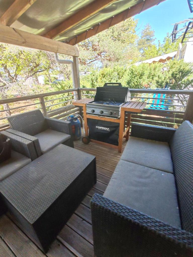 un porche grillagé avec des canapés et un barbecue dans l'établissement Mobil home 6 personnes, à Sainte-Croix-de-Verdon
