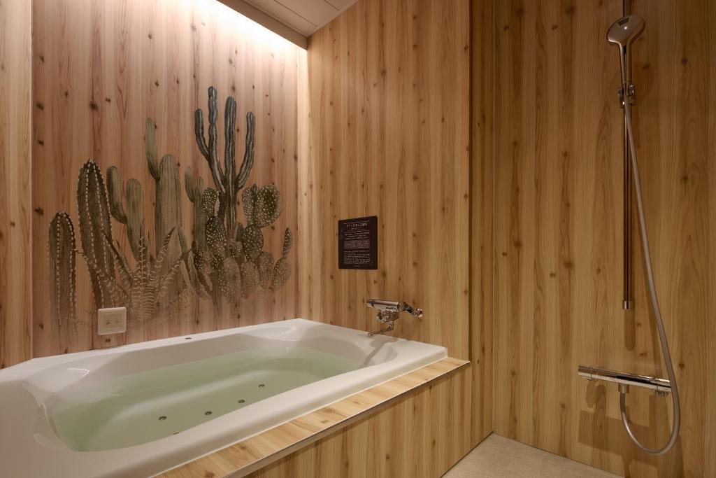 La salle de bains est pourvue d'une baignoire et d'un mur de cactus. dans l'établissement 袖ヶ浦c COAST HIKE HOTEL, à Sodegaura