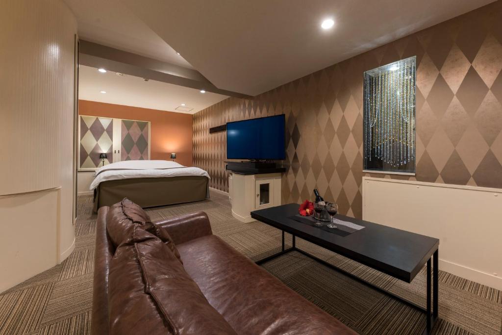 un salon avec un canapé et un lit dans l'établissement ホテル ジュエリージュエリー 十三, à Osaka