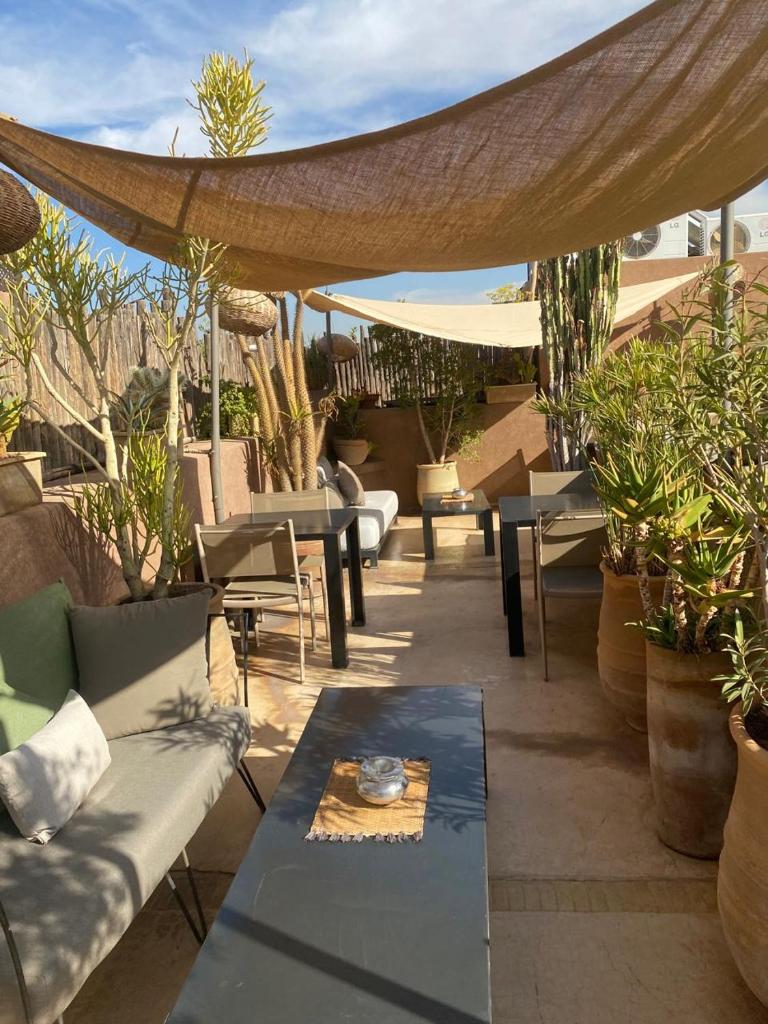 une terrasse avec des canapés, des tables et des plantes en pot dans l'établissement Riad Dar 73, à Marrakech