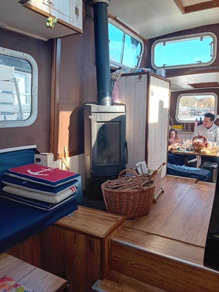 - un salon avec un poêle à bois dans un bateau dans l'établissement BOAT Judy proche PARIS, à Maurecourt