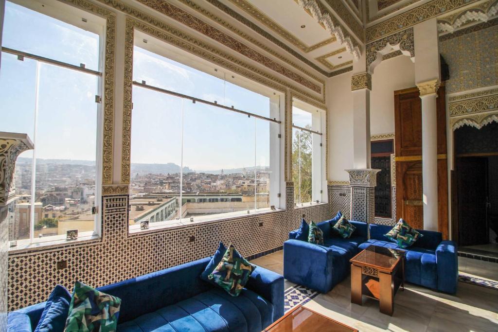 - un grand salon avec des canapés bleus et de grandes fenêtres dans l'établissement Riad Zaya Fes, à Fès