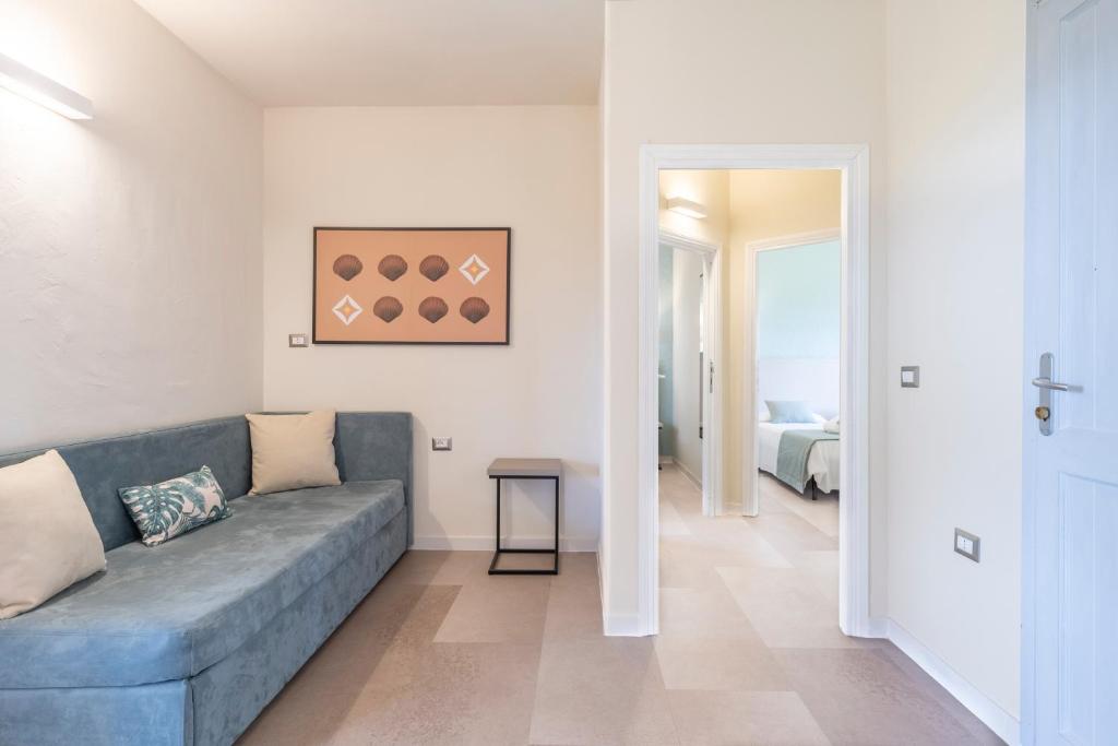 un salon avec un canapé bleu et une chambre dans l'établissement Mimose Beach Village, à Badesi