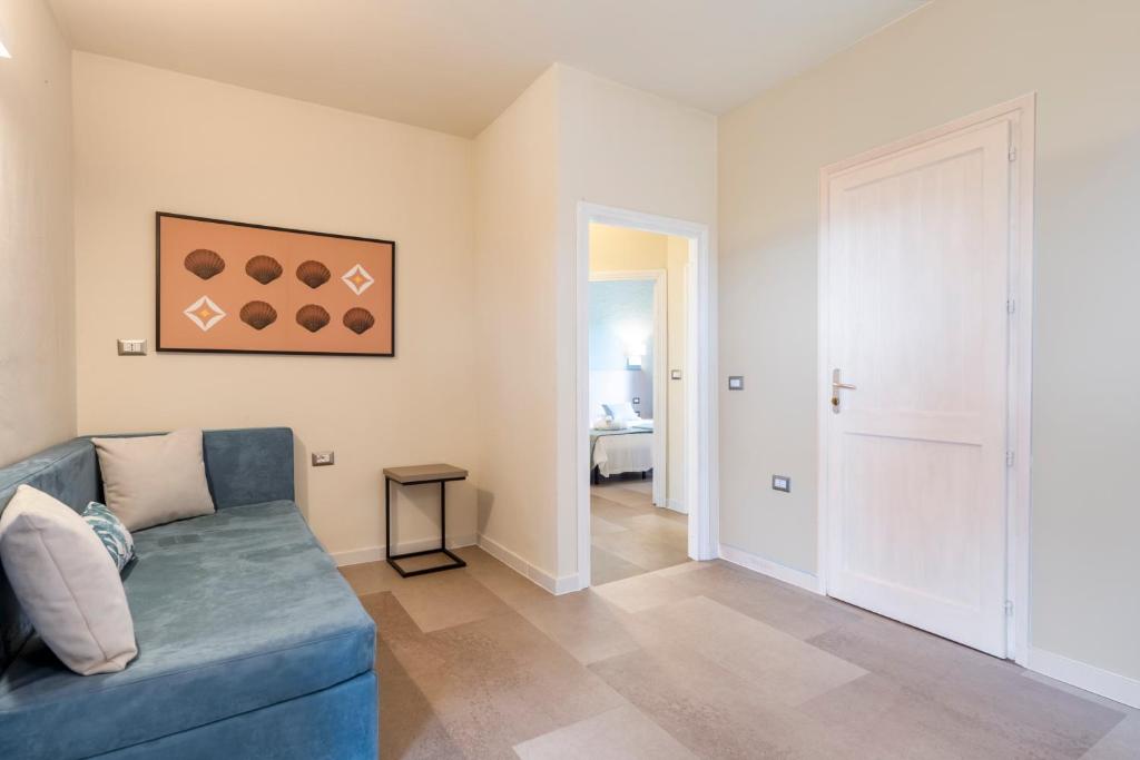 un salon avec un canapé bleu et un couloir dans l'établissement Mimose Beach Village, à Badesi