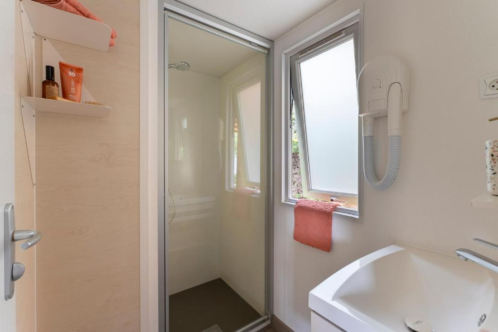 une salle de bain avec douche et lavabo dans l'établissement Camping Le Calypso 5 étoiles, à Torreilles