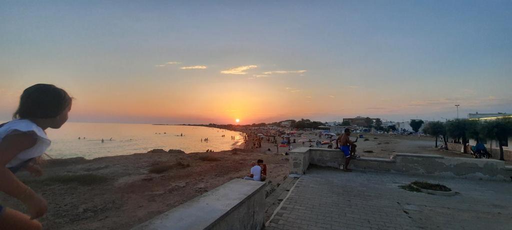 - un groupe de personnes sur une plage au coucher du soleil dans l'établissement VILLA PERLA del SALENTO con piscina, à Lido Marini