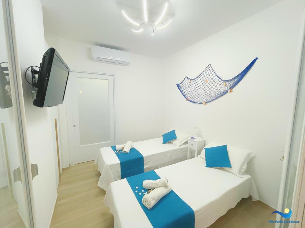 une petite chambre avec deux lits et une télévision dans l'établissement VILLA PERLA del SALENTO con piscina, à Lido Marini