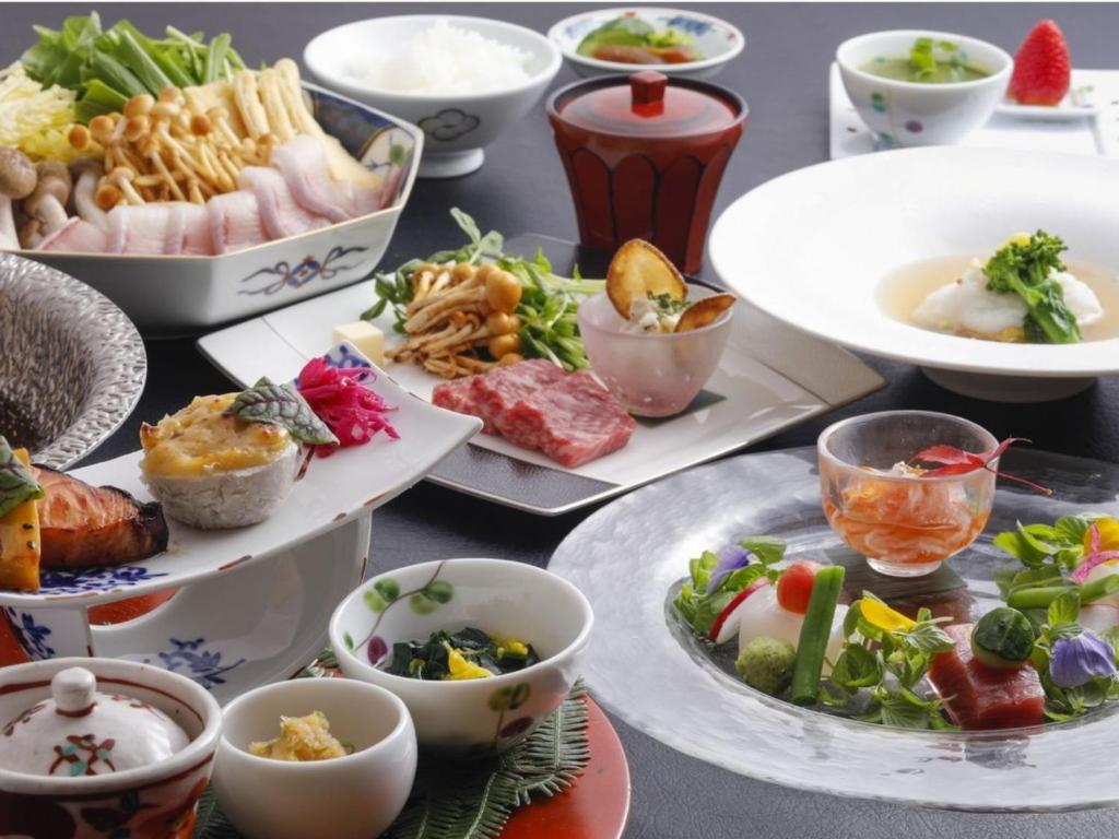 une table avec des assiettes et des bols de nourriture dans l'établissement Arima Hot Spring Ryokan Hanamusubi, à Kobe