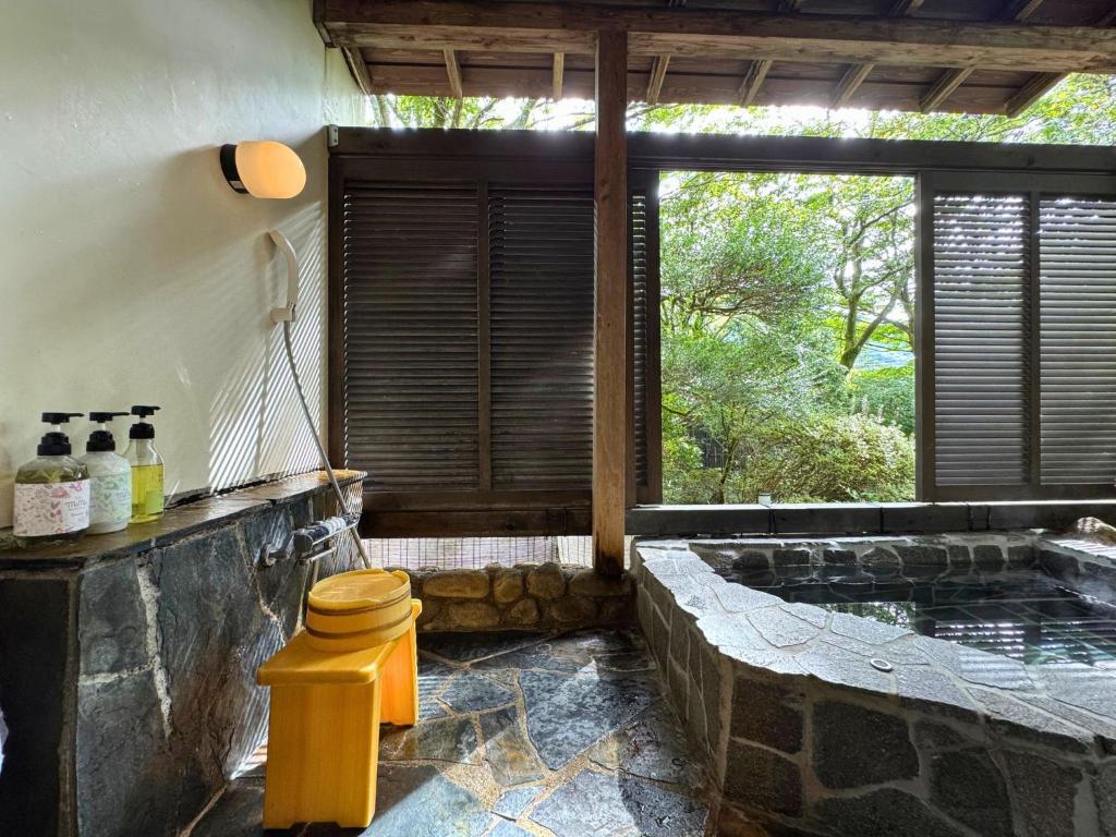 une salle de bains avec un jacuzzi et une fenêtre dans l'établissement Sengokuhara Shinanoki Ichinoyu, à Hakone