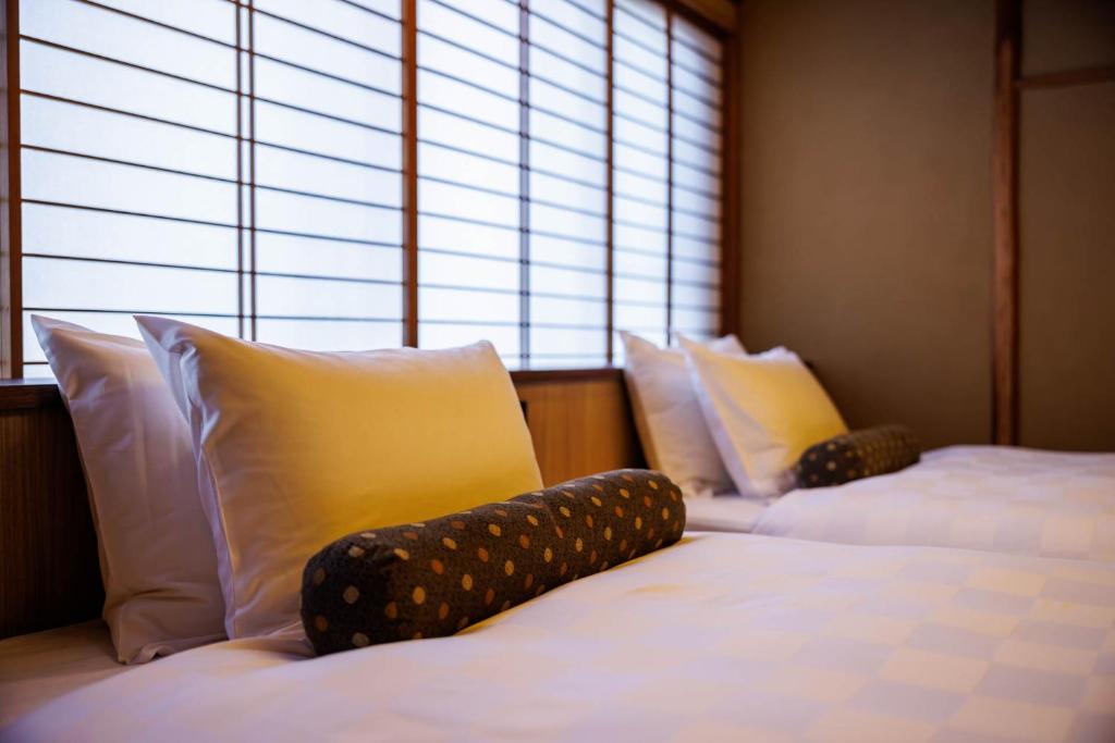 - 2 lits avec oreillers dans une chambre avec fenêtre dans l'établissement Kyoto Ryokan SAKANOUE, à Kyoto