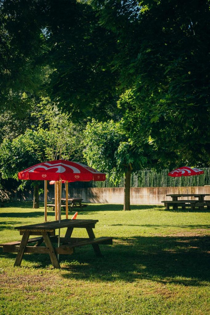 - deux tables de pique-nique avec des parasols rouges dans un parc dans l'établissement Camping intercommunal de Beaurepaire, à Beaurepaire 4 autres photos