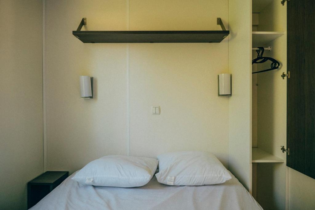 - un lit avec 2 oreillers blancs dans l'établissement Camping intercommunal de Beaurepaire, à Beaurepaire