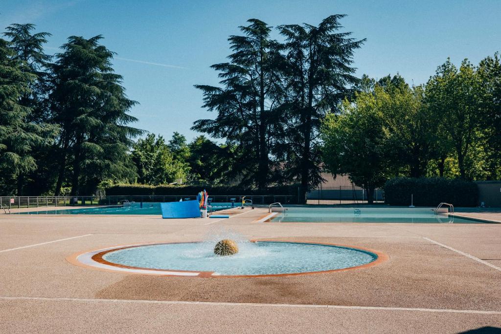 une fontaine au milieu d'un court de tennis dans l'établissement Camping intercommunal de Beaurepaire, à Beaurepaire