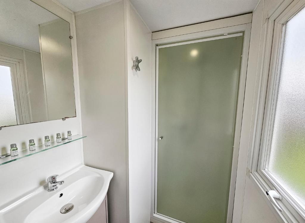 une salle de bain avec une douche, un lavabo et un miroir dans l'établissement Loc younes, à Litteau