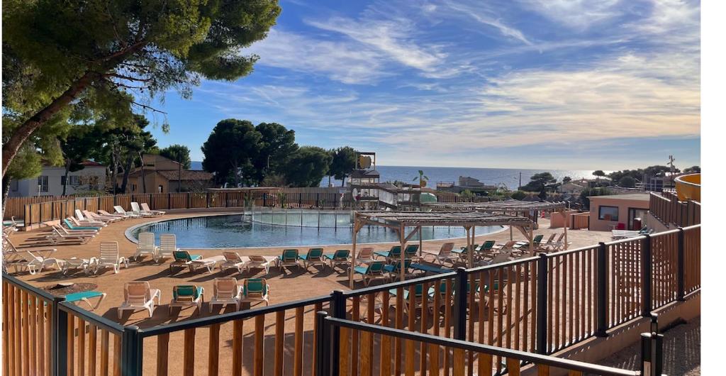 une piscine avec des chaises longues et une clôture dans l'établissement Bungalow Mobil Home Carry-le-rouet, à Carry-le-Rouet