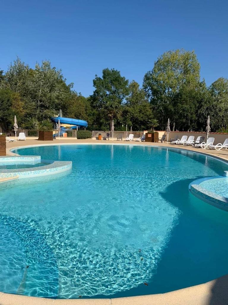 une grande piscine avec de l'eau bleue et des chaises dans l'établissement Mobil home, à Angles