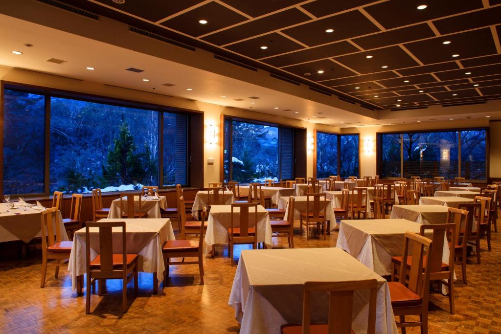 un restaurant avec des tables et des chaises blanches et des fenêtres dans l'établissement Fuji View Hotel, à Fujikawaguchiko