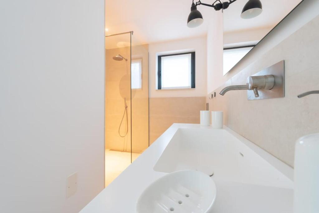 une salle de bain blanche avec un lavabo et une douche dans l'établissement Villa Vogue - IsulaTravel, à Avola