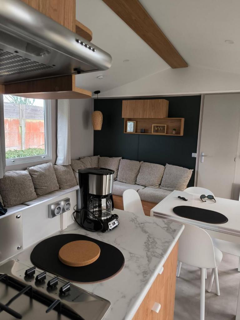 Il dispose d'une cuisine et d'un salon avec une cuisinière et un canapé. dans l'établissement mobil home luminosa 6pers tout équipé 3ch, à Saint-Jean-de-Monts
