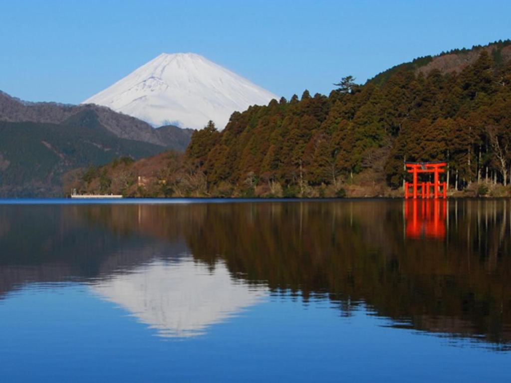 un reflet de montagne dans un lac avec une barrière rouge dans l'établissement Hotel Morinokaze Hakone Sengokuhara, à Hakone