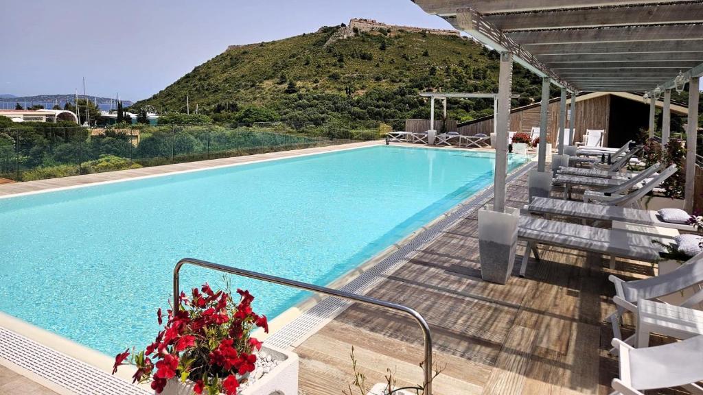 une piscine avec des chaises et une montagne en arrière-plan dans l'établissement A Point Porto Ercole Resort & Spa, à Porto Ercole