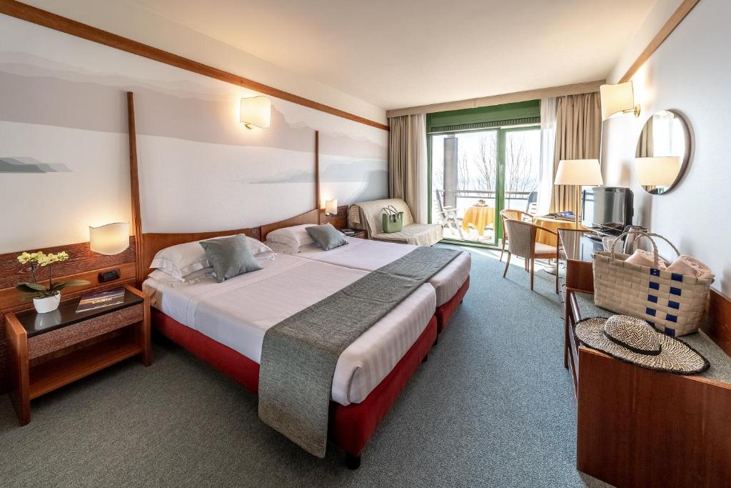une chambre d'hôtel avec un grand lit et un bureau dans l'établissement Hotel Du Lac et Bellevue, à Bardolino
