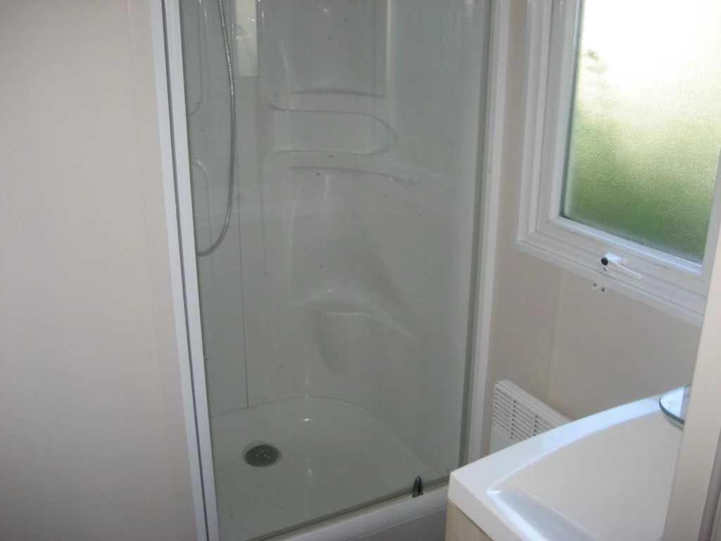 une salle de bain blanche avec une douche et un lavabo dans l'établissement Camping 3 étoiles - Parc aquatique - ccaehgc, à Déols 30 autres photos